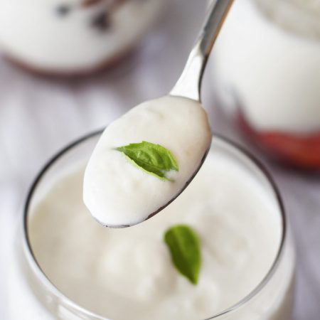 close-up-hand-holding-spoon-with-yogurt